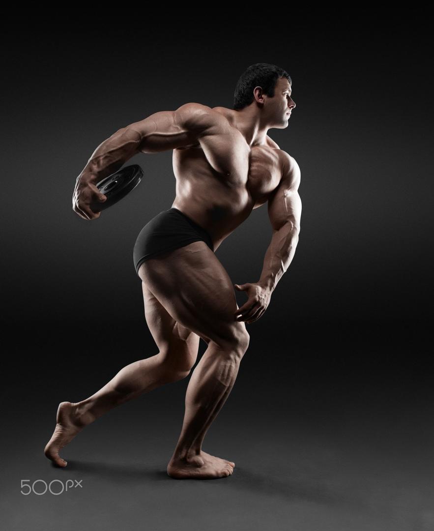 铁饼运动员 摆在黑背景的英俊的肌肉爱好健美者